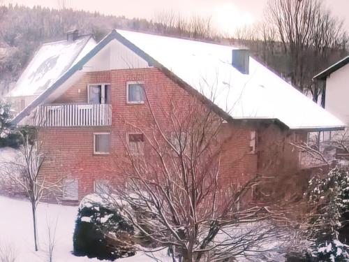 a red brick house with snow on the roof at Ferienwohnung Hoher Pön in Willingen