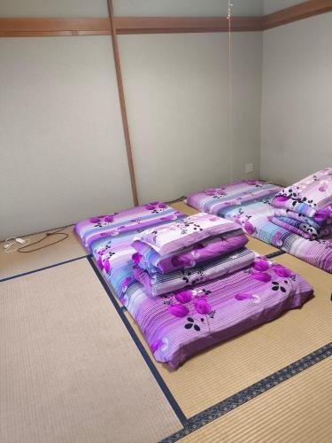 three beds in a room with purple sheets at 河津町天川旅館 in Shimo-sagano