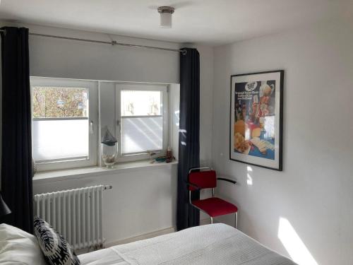 a bedroom with a red chair and two windows at Bed & Breakfast Bep - Klein aber fein in Naumburg