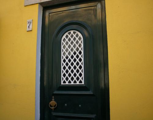 a green door with a window on a yellow wall at Casa 7 in Sintra