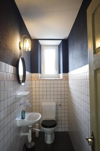 a bathroom with a toilet and a sink and a window at ReLiving - Historic City Apartment in Lucerne