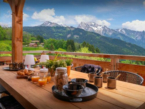 a wooden table with food on it with mountains in the background at Chalet Sivara - OVO Network in Manigod