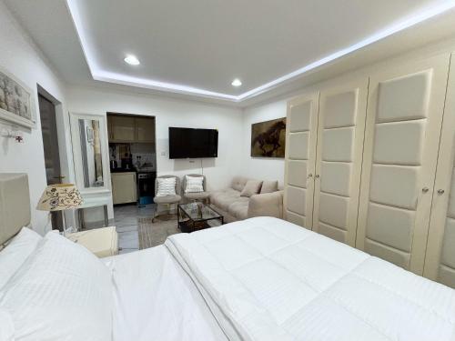 a white bedroom with a bed and a living room at Cozy Private Room with Kitchen & Private Bathroom 12 in Abu Dhabi