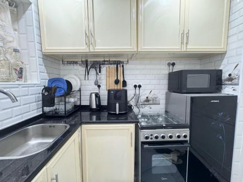 a kitchen with a sink and a stove and a microwave at Cozy Private Room with Kitchen & Private Bathroom 12 in Abu Dhabi