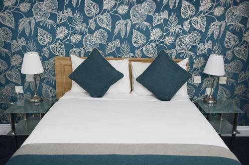 a bedroom with a bed with blue and white wallpaper at Basingstoke Hotel in Hook