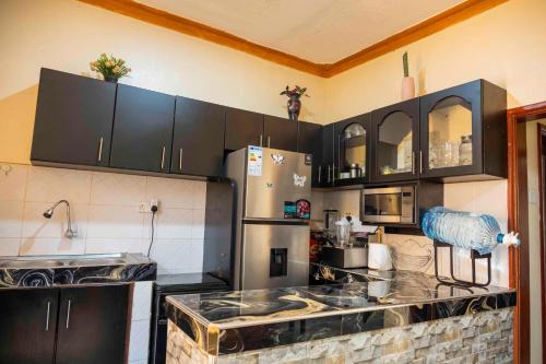 a kitchen with black cabinets and a stainless steel refrigerator at Urban Escape Apartment in Mbarara