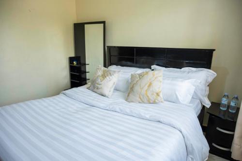 a large white bed with white sheets and pillows at Urban Escape Apartment in Mbarara
