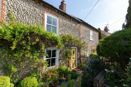 a brick house with ivy on the side of it at Bella's Cottage in Stiffkey