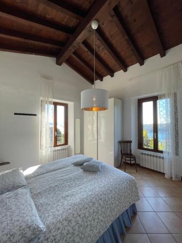 a bedroom with a large bed and two windows at Agriturismo Valsiniga - Your Private Family Retreat on Lake Garda Saló in Salò