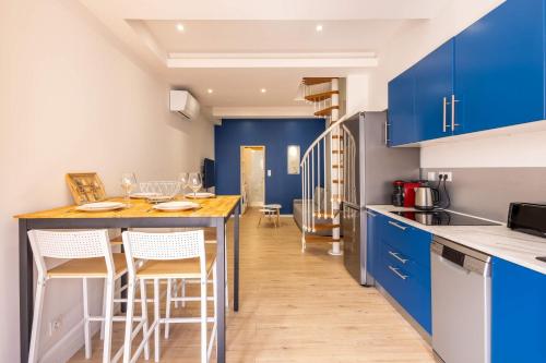 a kitchen with blue cabinets and a table with chairs at La Maison de lOrb in Valras-Plage