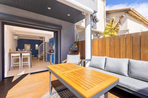 a patio with a couch and a wooden table at La Maison de lOrb in Valras-Plage