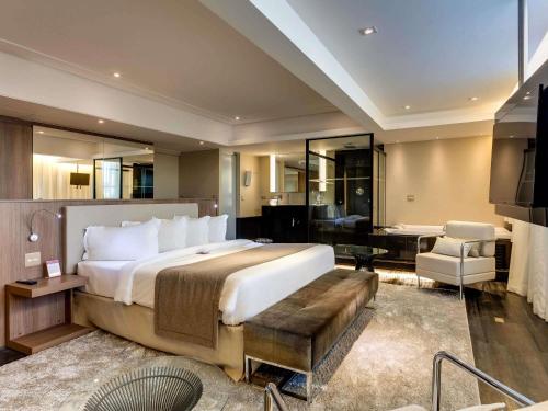 a bedroom with a large bed and a living room at Mercure Belo Horizonte Lourdes in Belo Horizonte