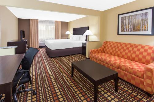 a hotel room with a bed and a couch at Days Inn & Suites by Wyndham Davenport East in Davenport