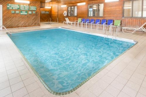 a large swimming pool in a room with chairs at Days Inn & Suites by Wyndham Davenport East in Davenport
