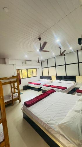 a room with several beds in it with a ceiling at Hotel GANANJAYA in Gokarna