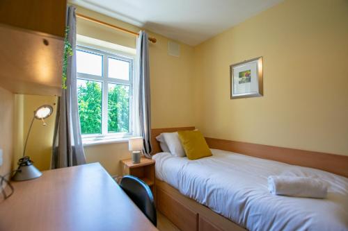 a room with two beds and a desk and a window at Spacious 4-Bed Central Limerick Group Retreat in Limerick
