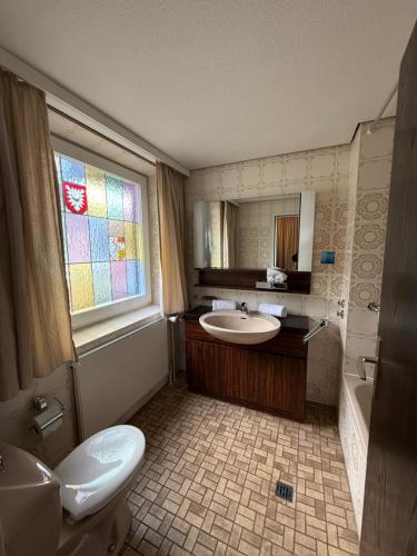 a bathroom with a sink and a toilet and a window at Hotel Stadt Lübeck in Timmendorfer Strand