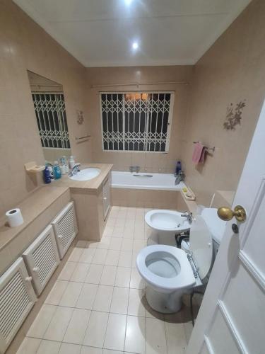 a bathroom with a toilet and a sink and a tub at Peaceful Corner Stay in Durban
