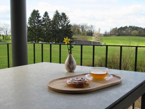 a table with a cup of tea and a vase with a flower at Landhaus de Bel in Hergenrath