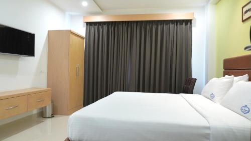 a hotel room with a bed and a television at Hotel Sri Ram Grand in Vijayawāda