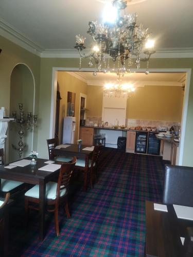 a dining room with tables and chairs and a chandelier at Granville Guest House in Dyce