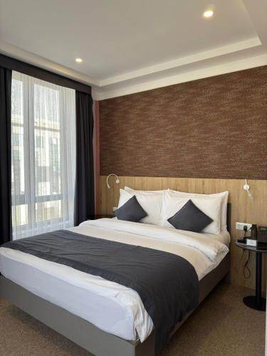 a bedroom with a large bed and a large window at Graf Hotel in Shymkent
