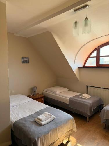 a room with two beds in a attic with a window at Hotel City in Gniezno