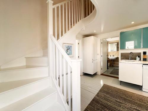 a white staircase in a kitchen with white cabinets at Spinney's Boathouse by The Suffolk Cottage Collection in Thorpeness