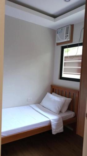 a small bedroom with a bed and a window at JAL Transient House in Hinoba-an