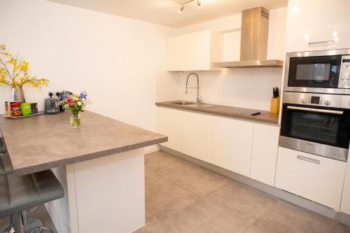 a kitchen with white cabinets and a counter top at Panorama House, Modern 3-Bedroom Apartment 3, Oxford in Oxford