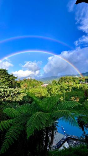 a rainbow in the sky over a lake with a forest at Hotel Villa Aventura in Cuetzalán del Progreso