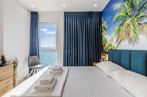 a bedroom with a large white bed with blue curtains at The Butterfly Apartment | Seafront & Amazing Views by PikHost in Lezhë