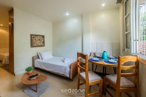 a room with a table and a bed and a table and chairs at Studio in Condo w/ Pool in Downtown QUI0605 in Poços de Caldas