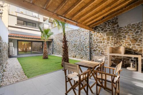a patio with a table and chairs and a yard at PALHOTAS GUEST HOUSE - Apartamento Jardim Santa Bárbara in Braga