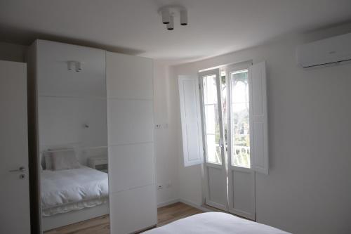 a white bedroom with a bed and a window at Villa Serena - Armonia Apartment in Tirrenia