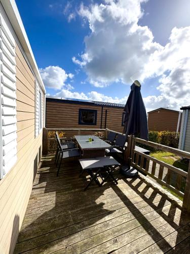 a patio with a table and an umbrella on a deck at Renesse Chalet in family friendly area in Renesse