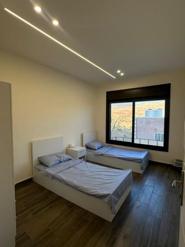 two beds in a room with a large window at Ranachalet-1 in Ash Shāghūr