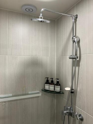 a shower with three bottles on a shelf in a bathroom at 여유스테이 in Suwŏn-yŏk