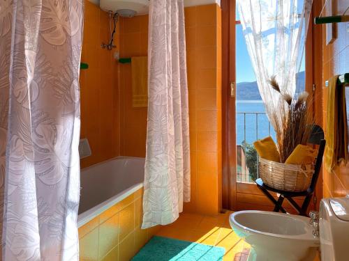 a bathroom with a tub and a toilet and a window at Appartamento Pascià al Lago in Oggebio
