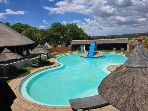 a pool at a resort with chairs and a slide at Beverly Hills Lodge in Fourways