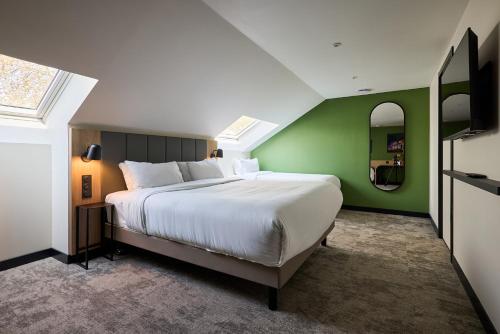 a bedroom with a large bed and a green wall at Campanile Le Mans - Arnage in Arnage