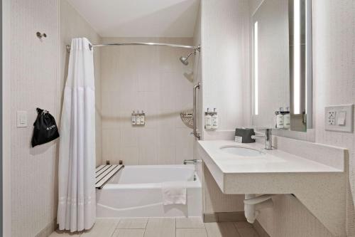 a white bathroom with a tub and a sink and a shower at Holiday Inn Oxnard - Ventura by IHG in Oxnard