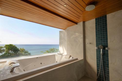 a bathroom with a tub and a window with the ocean at Bluesiam Villa - SHA Certified in Surin Beach