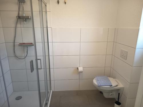 a white bathroom with a shower and a toilet at Haus Lützowallee in Aurich