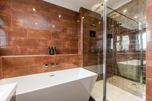 a bathroom with a tub and a glass shower at Luxury Beach Escape Pool Table & Private Parking in Broadstairs