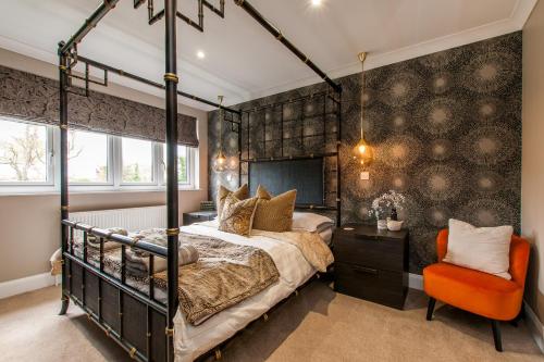 a bedroom with a canopy bed and an orange chair at Luxury Beach Escape Pool Table & Private Parking in Broadstairs