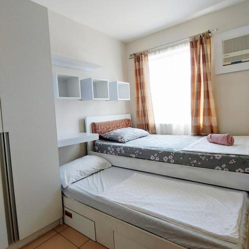 two beds in a small room with a window at Nanay's Condotel in Sampong