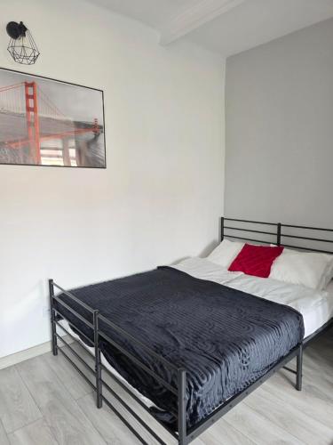 a bed in a white room with a black frame at GreatLoft Apartament in Oświęcim