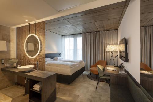 a bedroom with a bed and a sink and a mirror at ARCOTEL Tabakfabrik Linz in Linz