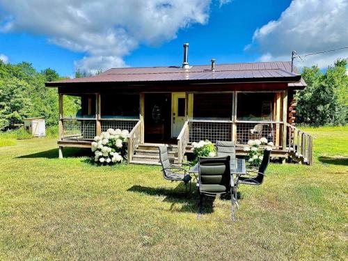 a house with a porch and chairs in the grass at Connie's Little House in Elmira